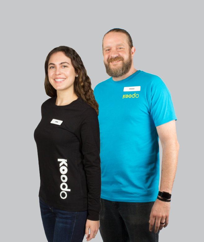 Female with a black, branded long sleeve shirt with a white Koodoo logo, Man to her right has a teal promotional t shirt with a lime green Koodoo logo on his left chest
