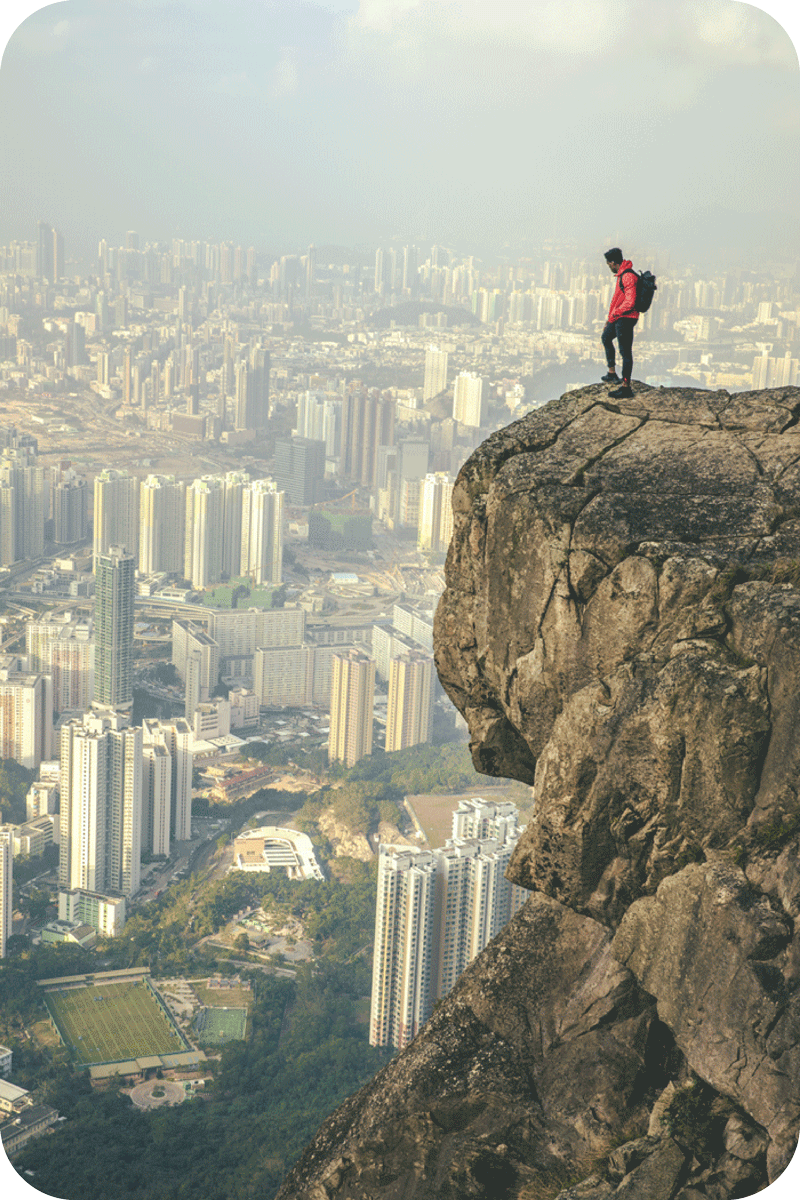 man looking at city from mountain side - rounded edges